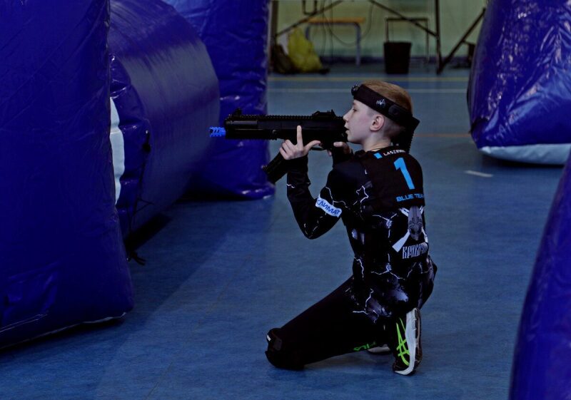 Мальчик в синей команде прицеливается из оружия LASERWAR.